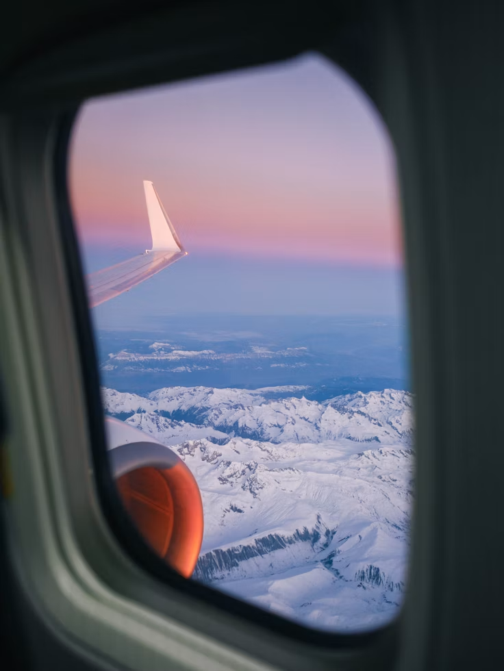 Snow-capped mountains seen through an airplane window