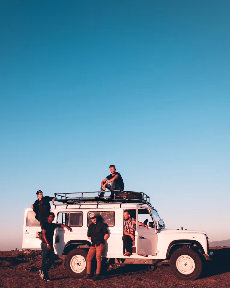 Group of travelers on a Land Rover at sunset