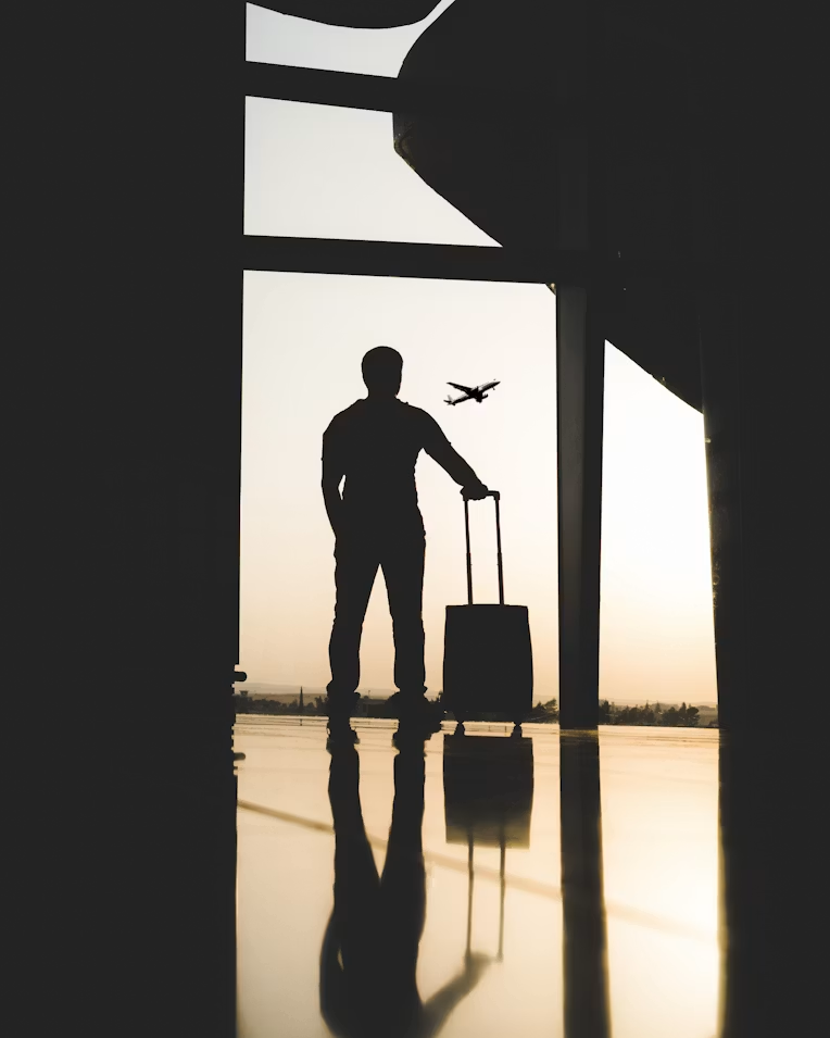 Traveler silhouette with luggage at airport sunrise